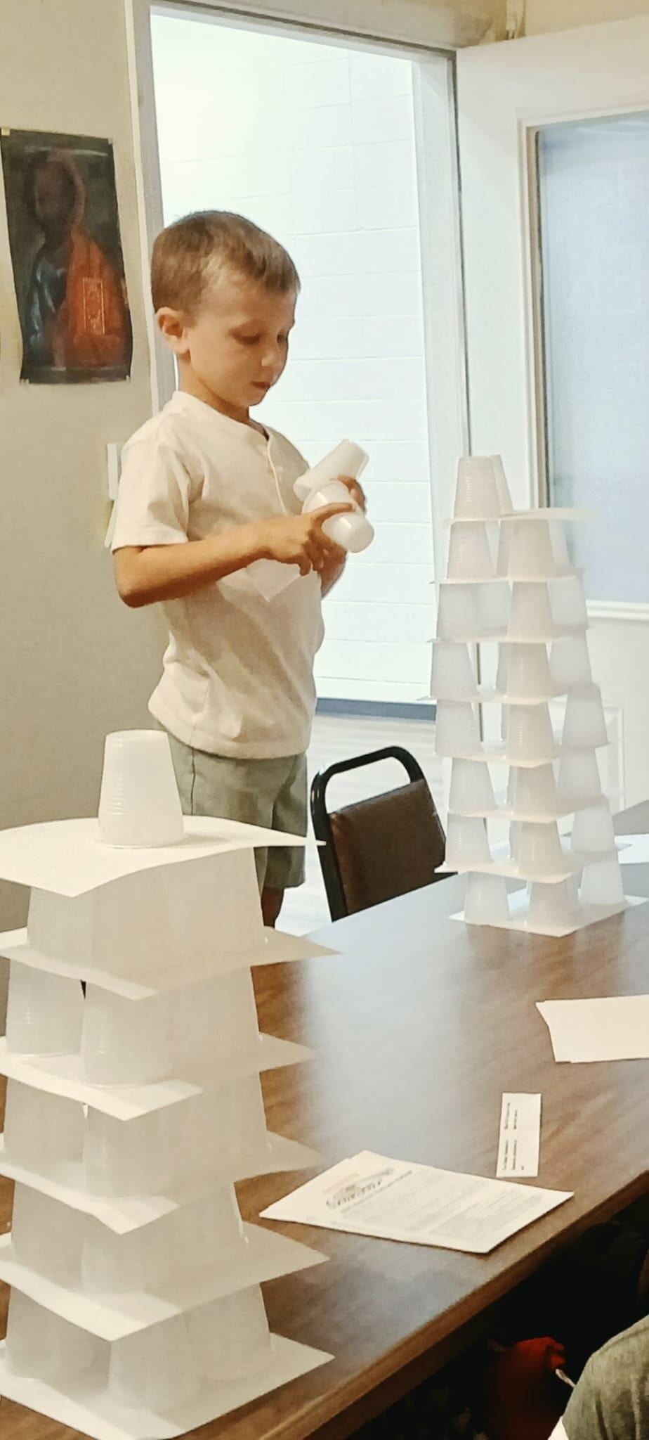 Young boy carefully stacking cups to build his Tower of Babel