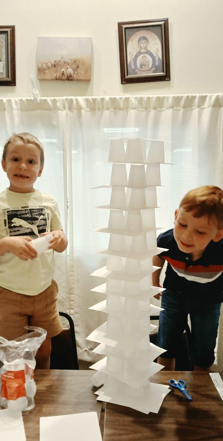 Two boys proudly standing beside their tall Tower of Babel