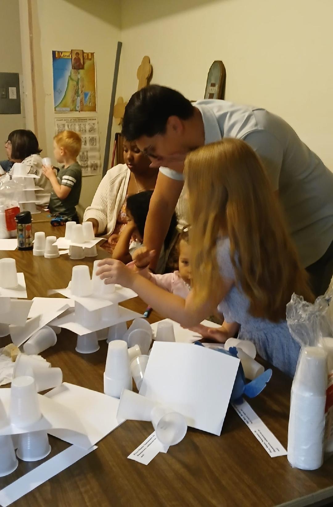Parent helping a young child place the next layer on their Tower of Babel — a moment of learning and togetherness in Sunday School